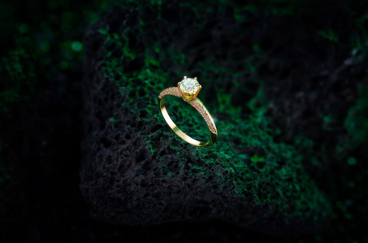 jewellery, jewellery photography for Mikus Diamonds brand - engagement ring in yellow gold placed on lava rock with green light in the background, product photography, product photographer, eshop, ecommerce